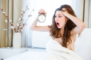 Stressed woman waking up with alarm